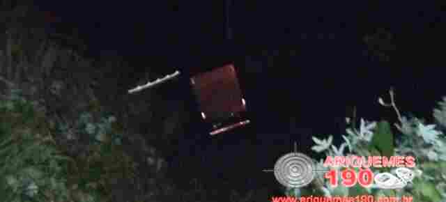 Caminhoneiro perde controle de veículo ao fazer ultrapassagem em curva e cai em ribanceira de rio